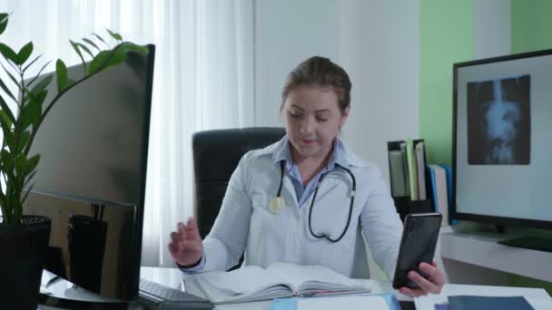 現代医学、病院の従業員の女性は、ビデオを介してオンラインで病気や風邪カウンセリングの症状を記録患者とオンラインで動作します - 映像、動画