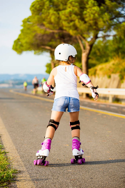 Una piccola ragazza caucasica principiante rullo. Serata estiva sulla costa, la pista ciclabile di Capodistria, Slovenia - Foto, immagini