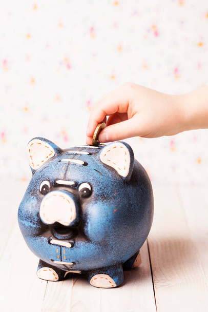 Little child puting a coin into a piggy bank. Focus on the hand. Copy space. - Photo, Image