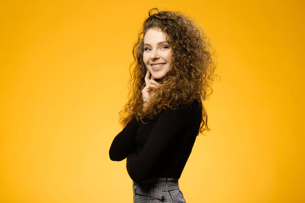 Pretty girl with curly hair isolated on yellow background - Фото, изображение