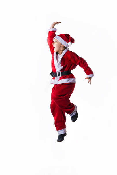 Маленькая кавказская девочка в костюме Санта Клауса прыгает на белом фоне. Копирование пространства
. - Фото, изображение