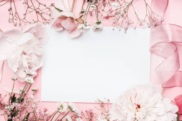 White blank card with pastel flowers and ribbon on pink pale background, floral frame. Creative greeting, Invitation and holiday concept - 写真・画像