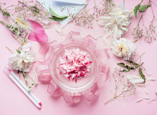 Creative Pink Florist workspace. Pretty floral decoration arrangement with pink roses and plant leaves in glass vase with water and florist decoration equipment, top view. Holiday concept - Fotó, kép