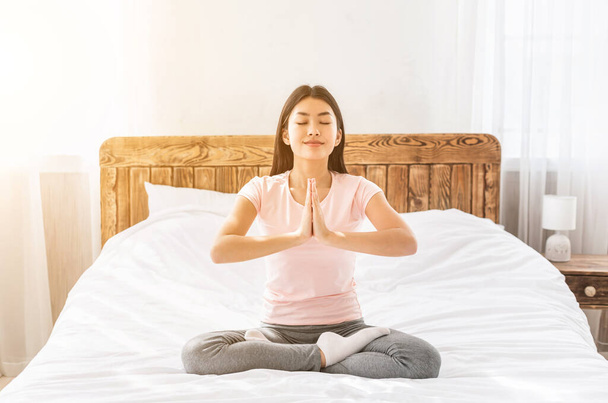 Chica relajante haciendo yoga sentada en posición de loto en casa
 - Foto, imagen