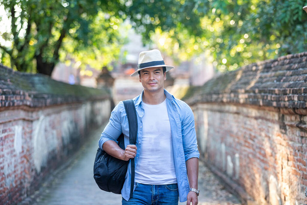 Travel and tourism. Young caucasian man traveling in the morning at temple in old city of Ayutthaya. Traveler man walking on ancient ruins street in Ayutthaya old city. Thailand. - Foto, Imagem