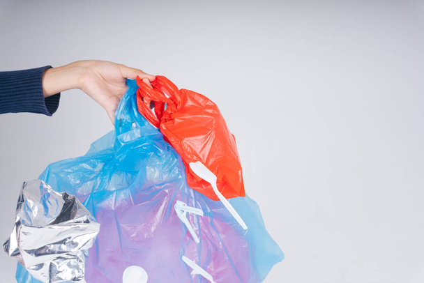 Mano de mujer reciclando residuos de bolsas de plástico aislar sobre fondo blanco. - Foto, imagen
