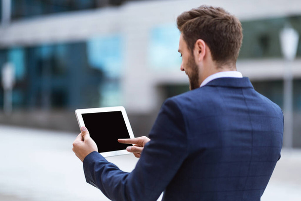 Business executive holding tablet computer with blank screen near office building, mockup for design - Photo, Image