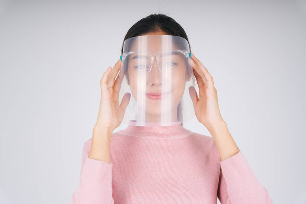 Close up - New normal fashion portrait. Asian thai long dark hair woman in pink sweater wearing face shield isolate over white. - Foto, Imagen
