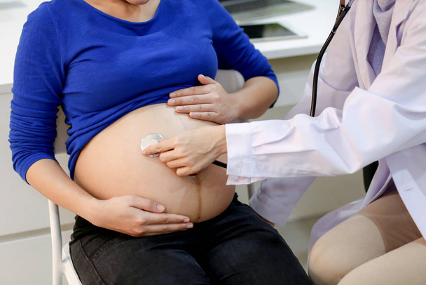 Лікар оглядає вагітність. Молодий лікар вивчає вагітну жінку в клініці. Вагітна жінка-лікар зі стетоскопом
. - Фото, зображення