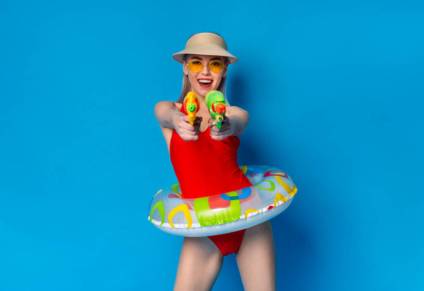 Joyful Millennial Girl In Swimsuit Playfully Aiming With Water Guns At Camera - 写真・画像