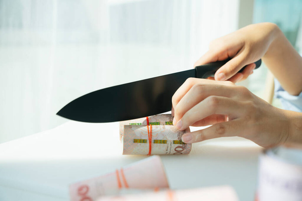 Maliyet indirimi. İşyeri sahibi, bıçak dilimleme banknotu kullanmaktan tasarruf ediyor. - Fotoğraf, Görsel