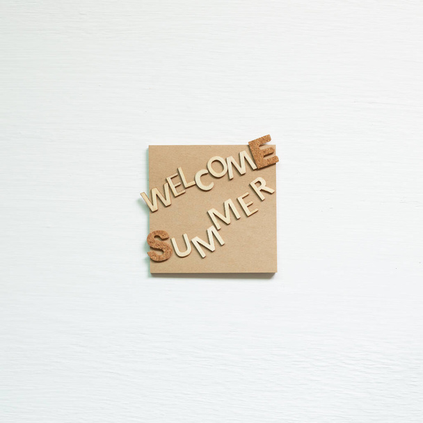 Palabra 'Bienvenido verano' en bloc de notas sobre fondo blanco. Concepto vacaciones de verano. vista superior
 - Foto, Imagen