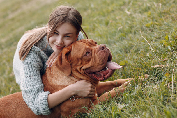Dogue de Bordeaux oder Französische Dogge mit junger Frau auf der Freiluftparkwiese - Foto, Bild
