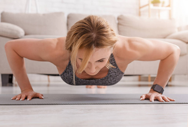 Push-ups at home. Strongly fitness woman doing exercises on mat - Photo, Image