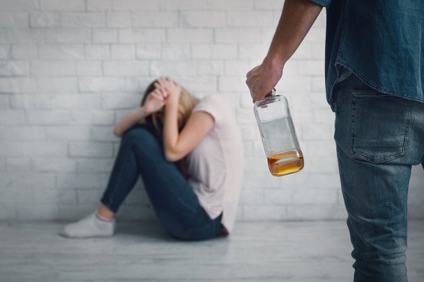 Agresif alkolik mağduruna yardım. Kadın, elinde şişeyle kendini kocasını yumruklamaya kapatıyor. - Fotoğraf, Görsel