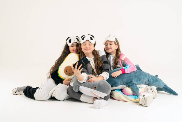 Roztomilé dospívající dívky v kigurumi a spánkové masky s úsměvem a natáčí video. Selfie - Fotografie, Obrázek