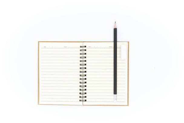 Czarny ołówek i biały gumka umieszczone w prawym górnym rogu notebooka, wszystkie umieszczone na białym tle. - Zdjęcie, obraz