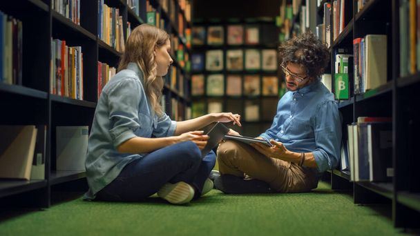 University Library Study: Smart Caucasian Girl Sitting and Talented Hispanic Boy Sitting Cross-Legged On the Floor, Talk, Use Laptops, Collaborate and Discuss Paper, Study and Prepare for Exams - Fotoğraf, Görsel