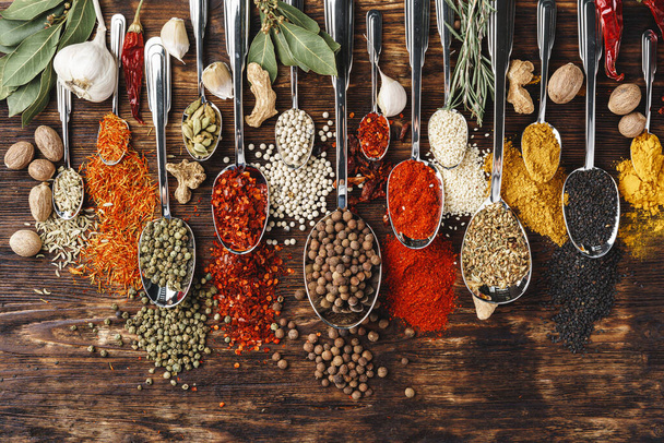 Spices in spoons on dark wooden background top view - Fotó, kép