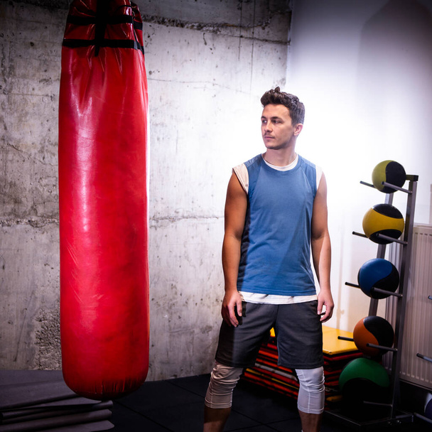 Young male standing in front of a punching bag during his boxing session - Foto, Imagem