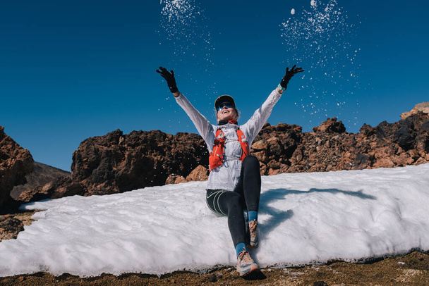 Ευτυχισμένη νεαρή πεζοπόρος γυναίκα απολαμβάνει το χιόνι στο βουνό - Φωτογραφία, εικόνα