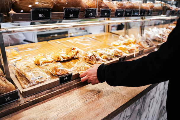 Klant koopt vers bakbrood bij bakkerij shef shop in winkelcentrum. - Foto, afbeelding