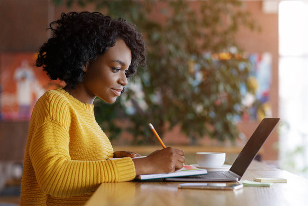 Молодая чернокожая девушка ищет работу онлайн в кафе
 - Фото, изображение