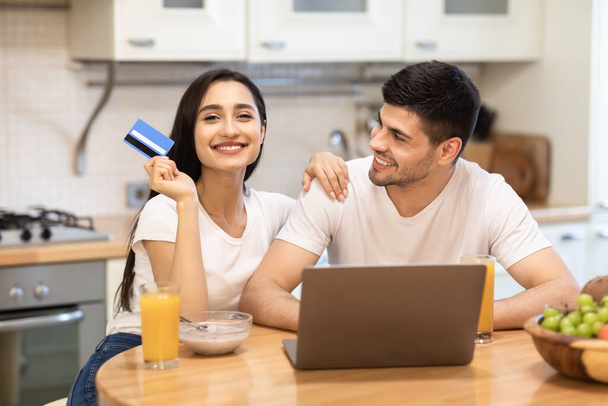 Ευτυχισμένο ζευγάρι κρατώντας χρεωστική κάρτα για online αγορές - Φωτογραφία, εικόνα