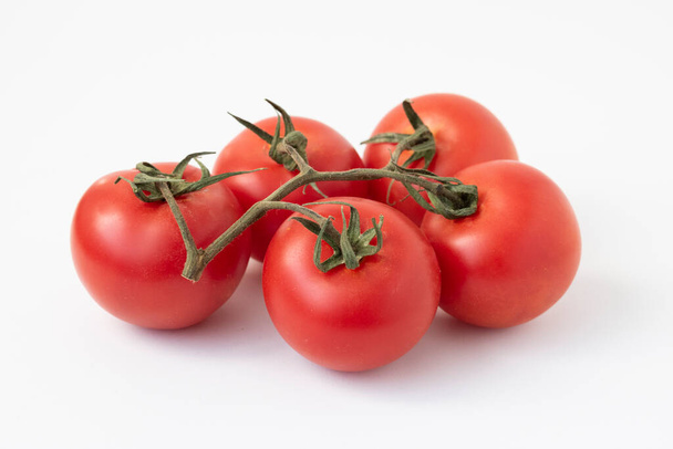 Tomaten an der Reben mit einem Schneideweg, isoliert auf weiß. Das Bild ist voll fokussiert, von vorne nach hinten. - Foto, Bild