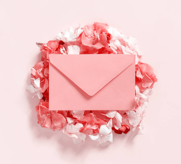Pink envelope on flowers  over a pink background  top view - Photo, Image
