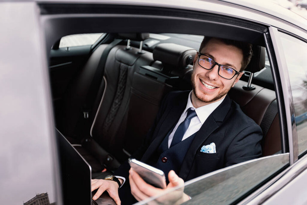 Biznesmen siedzi w luksusowym samochodzie patrząc przez okno - Zdjęcie, obraz