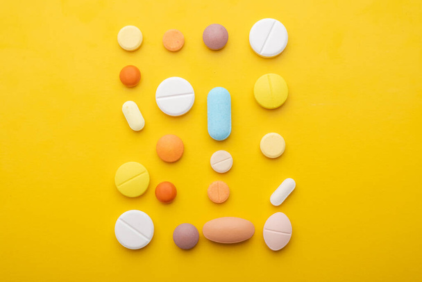 muchas píldoras diferentes sobre fondo amarillo
  - Foto, Imagen