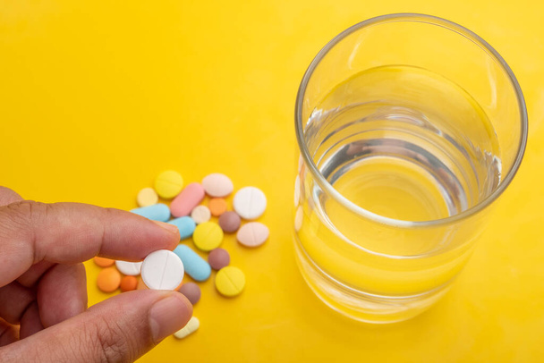 таблетки для рук, много различных таблеток на желтом фоне и стекле
  - Фото, изображение