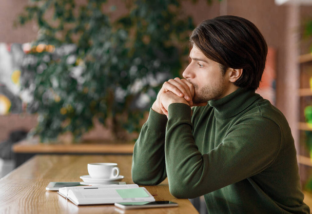 Pensive man zit alleen in het café, het drinken van koffie - Foto, afbeelding
