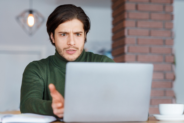Angry guy freelancer looking at laptop screen - Фото, зображення