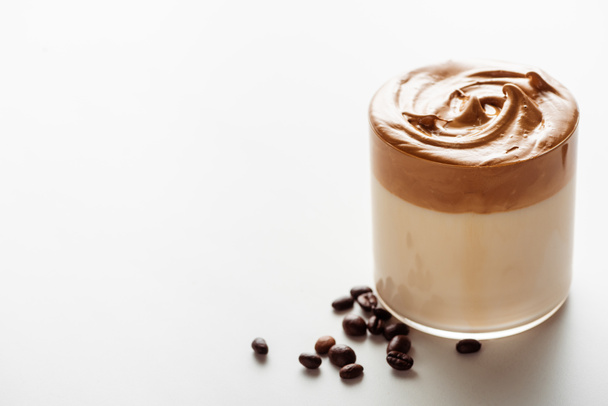 おいしいダルゴナコーヒー白を背景にコーヒー豆の近くのガラス - 写真・画像
