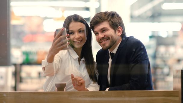 Happy young formaly dressed couple using cell phones and taking - Фото, изображение