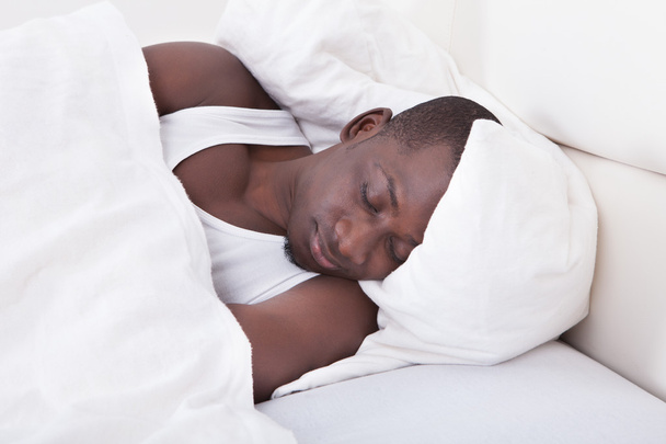 African Man Sleeping On Bed - Фото, изображение