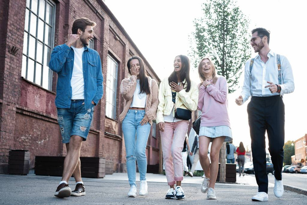 Group of happy young friends walking together, having fun on city street. - Valokuva, kuva