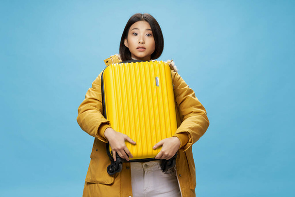 Ασιάτισσα ταξιδεύει με μια βαλίτσα στα χέρια της - Φωτογραφία, εικόνα