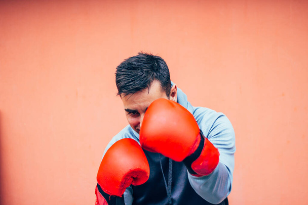 Frontansicht eines männlichen Boxers, der sein Gesicht mit Handschuhen bedeckt - Foto, Bild