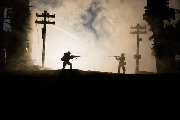 Army sniper with large caliber rifle standing in the fire and smoke. War Concept. Battle scene on war fog sky background, Fighting silhouettes Below Cloudy Skyline at sunset. City destroyed by war - Photo, Image
