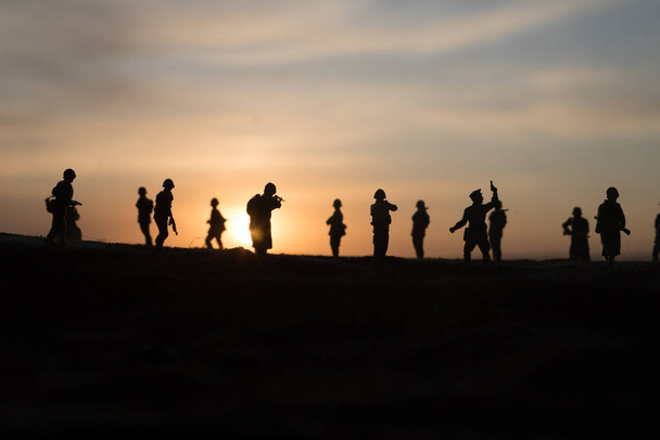 Koncepcja wojny. Wojskowe sylwetki walczące na tle mgły wojennej, żołnierze wojny światowej sylwetka poniżej zachmurzonego zachodu słońca. Skupienie selektywne - Zdjęcie, obraz