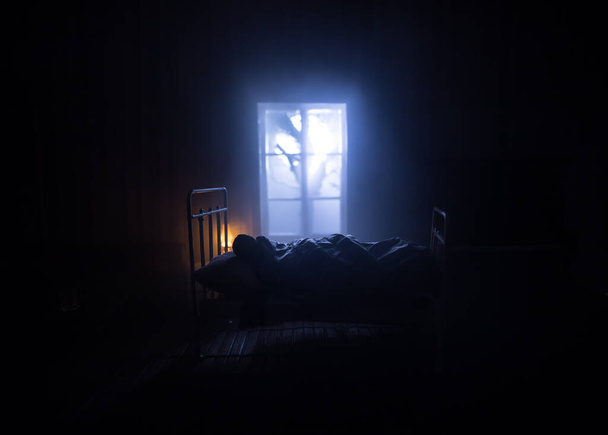 Mężczyzna spokojnie śpi w swoim łóżku w nocy. Realistyczna sypialnia domku dla lalek z meblami i oknem w nocy. Skupienie selektywne - Zdjęcie, obraz