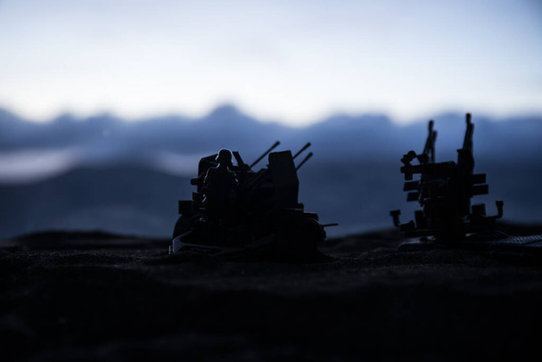 Silhouette of anti-aircraft cannon on battlefield during sunset time. Creative artwork table diorama. Selective focus. , World War Soldiers Silhouettes Below Cloudy Skyline at sunset. - Foto, Bild