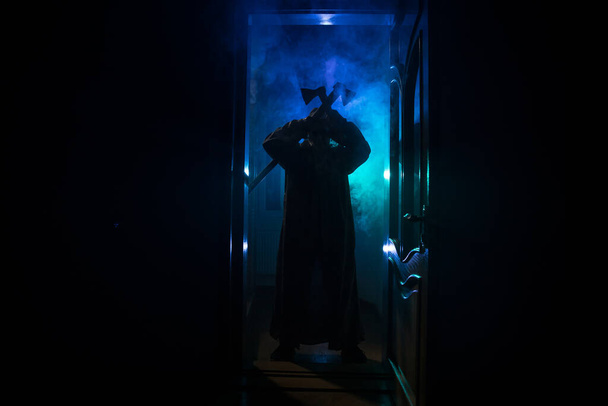Silhouet van een onbekende schaduwfiguur op een deur door een gesloten glazen deur. Spookachtig silhouet meisje 's nachts met rook op de achtergrond - Foto, afbeelding