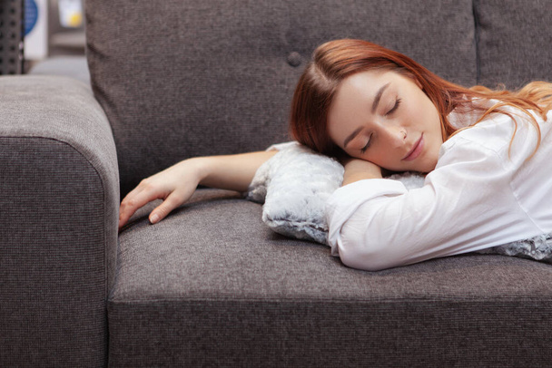 Woman sleeping on a couch, smiling joyfully with eyes shut - Photo, Image