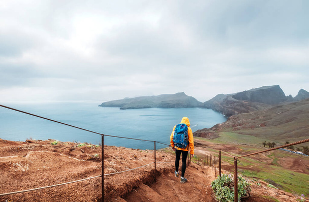 Young male backpacker hiking by footpath on Sao Lourenco headland with Atlantic ocean bay view in the end of February, Madeira island, Portugal. Active people around  World traveling concept image. - Zdjęcie, obraz
