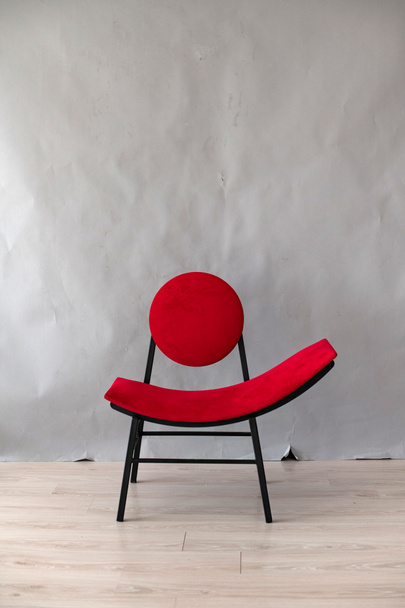 Czerwony stołek o niezwykłym kształcie. Minimalistyczne wnętrze w stylu poddasza. Czerwone meble na tle szarej ściany. Puste miejsce - Zdjęcie, obraz