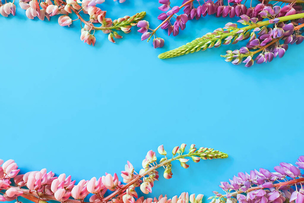 Virágkeret kék háttérrel. Nyári virágok Lapos fektetés, felülnézet. A meghívó vagy üdvözlőkártya formatervezésének vázlata. - Fotó, kép